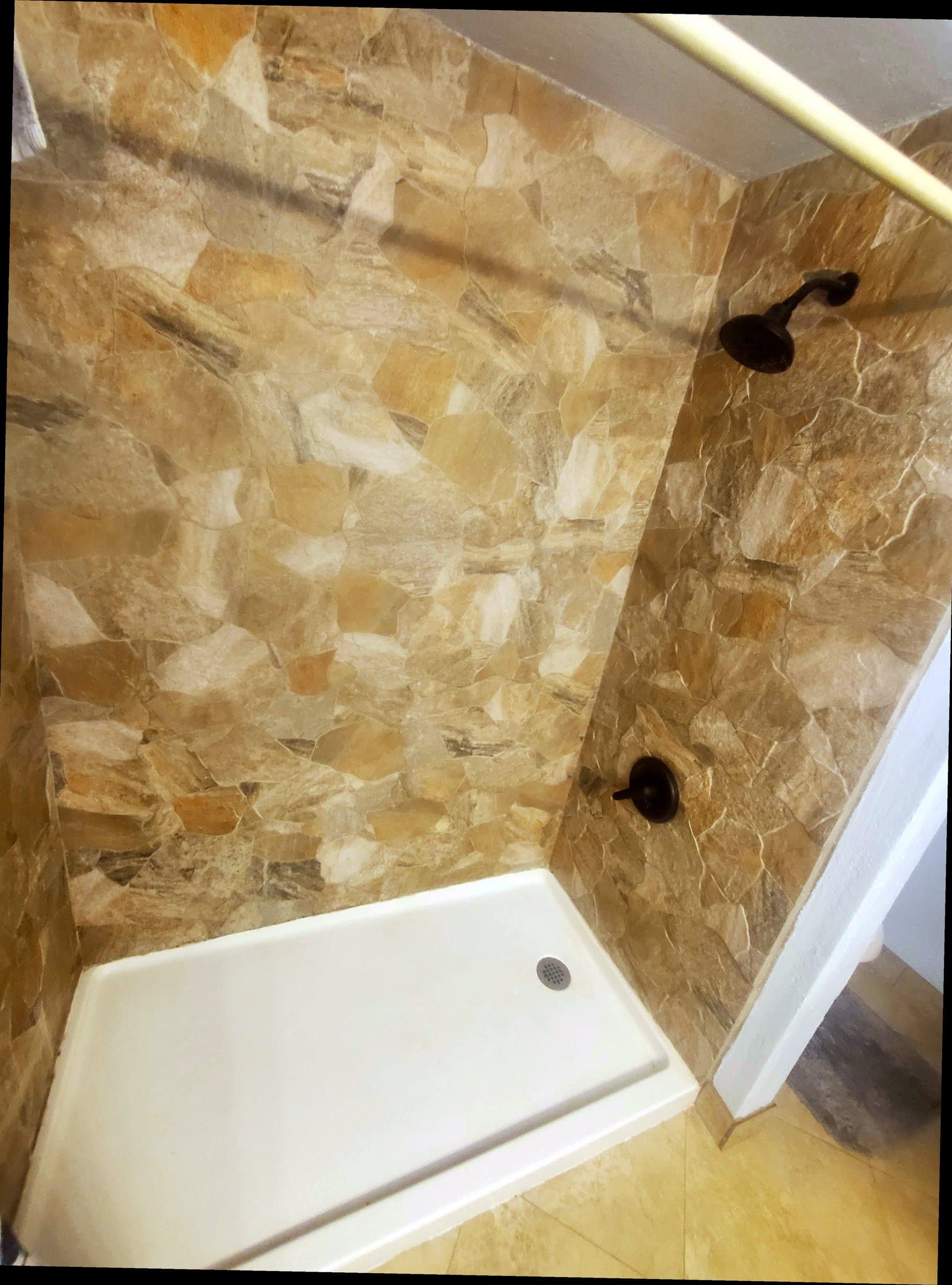 Stone-tile shower walls with dark bronze fixtures