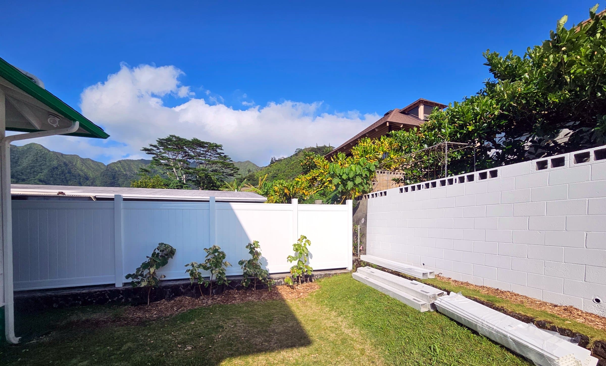 White vinyl privacy fence and freshly painted block wall under a blue sky